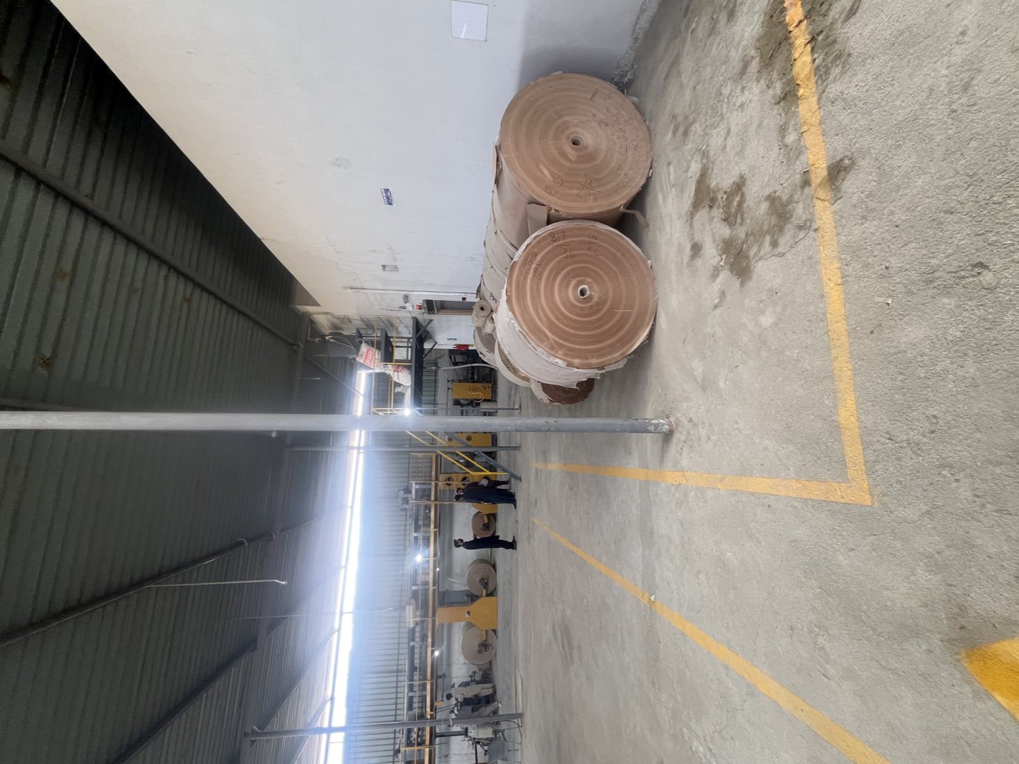 Kraft paper reels stocked on the plant floor in Karachi